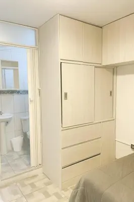 a white bedroom with a bed and a bathroom at Habitación en Miraflores completa in Lima
