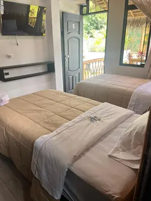 two beds in a hotel room with a mirror at Hotel Tulumayo Lodge in San Ramón