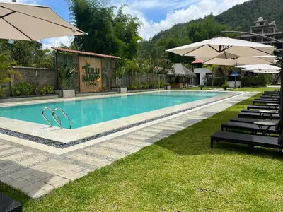 a swimming pool with chairs and umbrellas at a resort at Hotel Tulumayo Lodge in San Ramón