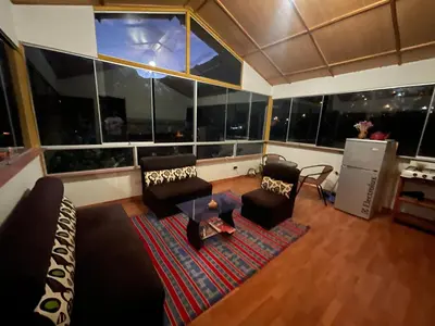 a living room with couches and a large window at Casa llegada del Sol in Ollantaytambo