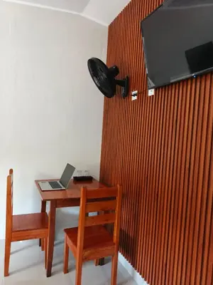 a desk with a laptop and a television on a wall at Alojamiento Oslo San Ramón in San Ramón