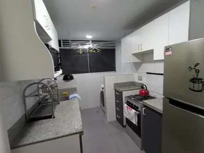 a small kitchen with a refrigerator and a stove at Departamento 03 dormitorios cerca Arena 1 in Lima