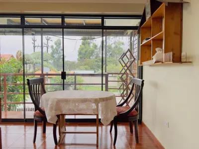 a dining room with a table and chairs and a large window at Casa Familiar TOVCA Oxapampa in Oxapampa