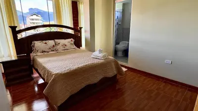 a bedroom with a bed and a bathroom with a toilet at Casa Familiar TOVCA Oxapampa in Oxapampa