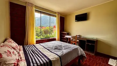 a bedroom with a bed and a large window at Casa Familiar TOVCA Oxapampa in Oxapampa