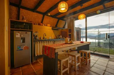 a kitchen with a refrigerator and a counter with stools at Alpine Cabin Quito in Cusco