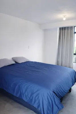 a blue bed in a white room with a window at Posada El Pino