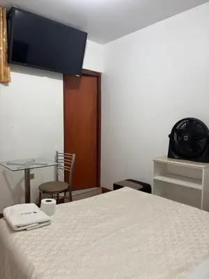 a room with a bed and a table and a clock at Hospedaje Ariana in Supe