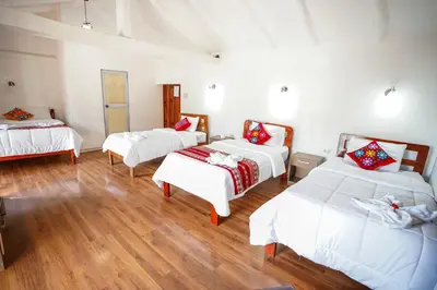 three beds in a room with wooden floors at Horizonte Hotels in Cusco