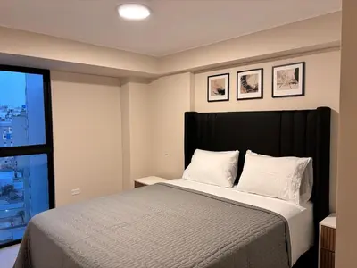 a bedroom with a bed with a black headboard and a window at Apartment in Larco - Miraflores in Lima