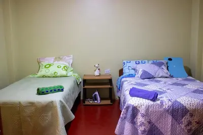 a bedroom with two beds and a table with a night stand at Posada del Carmen in Quillabamba