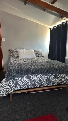a bedroom with a bed with a black and white comforter at Cozy room with kitchenette and private bathroom in Cusco
