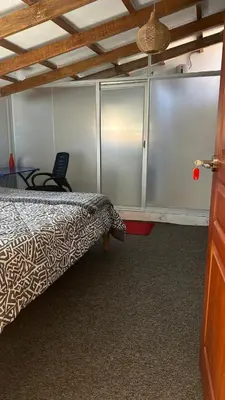 a bedroom with a bed and a chair and cabinets at Cozy room with kitchenette and private bathroom in Cusco