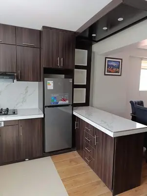 a kitchen with wooden cabinets and a black refrigerator at Sumaq Sky in Cusco