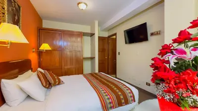 a bedroom with a bed and a television and flowers at Hotel Boutique Imperial in Cusco
