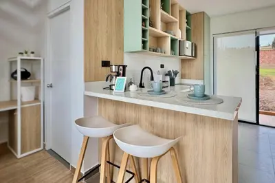 a kitchen with two white stools at a counter at Tiny House con Jacuzzi, Fogata y Starlink in Anta