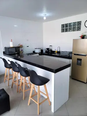 a kitchen with a counter with chairs and a refrigerator at Casa Bujama Playa y Piscina Privada in Bujama Baja