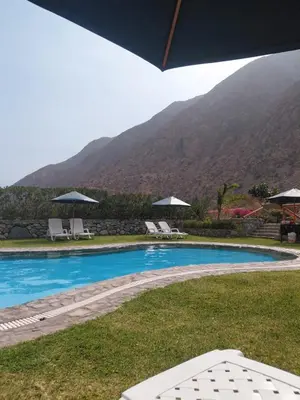 a swimming pool with chairs and umbrellas in front of a mountain at Casa de Campo en Santa Rosa de Quivez in Santa Rosa de Quives