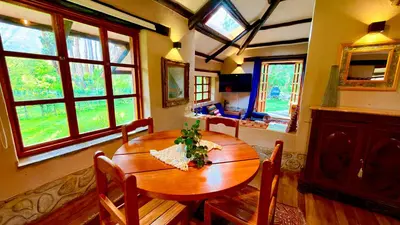 a dining room with a wooden table and some windows at Casa Munay in Urubamba