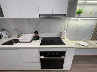 a white kitchen with a stove and a sink at The Modern Studios by Vibrant in Lima