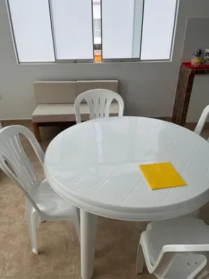 a white table with two white chairs and a yellow napkin at Departamento 201 in Punta Negra