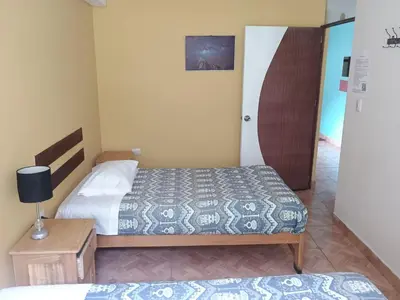 a small bedroom with two beds and a table at Refugio del Caminante in Ollantaytambo