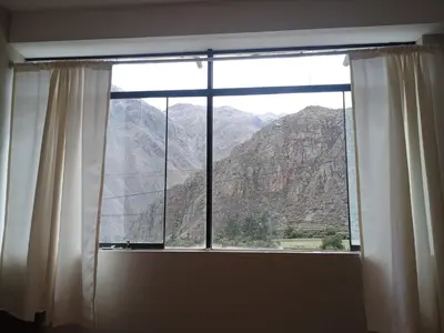 a window with a view of a mountain at Refugio del Caminante in Ollantaytambo