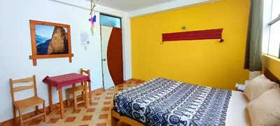 a bedroom with a bed and a table and a chair at Lycka Wasi Hospedaje in Ollantaytambo