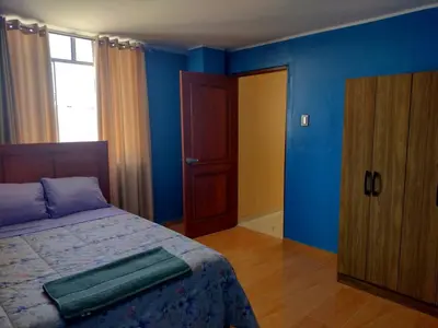 a bedroom with blue walls and a bed and a door at Casa Quevedo in Ica