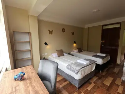 a hotel room with two beds and a table at Apu Garden Lodge in Urubamba