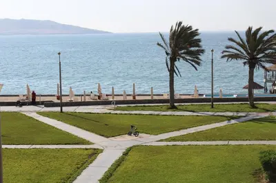 a walkway next to the ocean with palm trees at Departamento con Vista al Mar - Paracas - Condominio Nautico Las Velas in Paracas