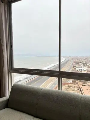 a couch sitting in front of a window looking out at an airport at Costanera Uno Vista al Mar in Lima
