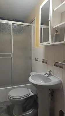 a white bathroom with a toilet and a sink at Boulevard home hostel - Lima Airport in Lima
