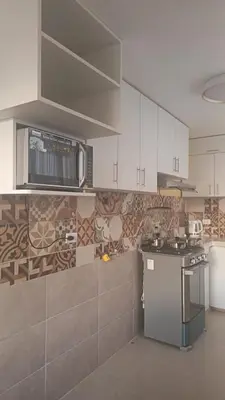 a kitchen with white cabinets and a microwave at Boulevard home hostel - Lima Airport in Lima