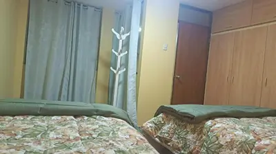 a bedroom with two beds and a window and a mirror at Boulevard home hostel - Lima Airport in Lima