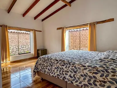 a bedroom with a bed and two large windows at Cancha Wasi A modern, cozy and fully equipped house in Urubamba
