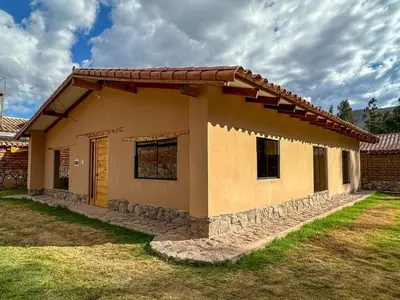 a small house in a yard with a cloudy sky at Cancha Wasi A modern, cozy and fully equipped house in Urubamba
