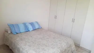 a bedroom with a bed with a blue pillow and white cabinets at Casa Frente al mar en club privado in Lurín