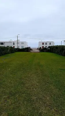 a large grassy field with buildings in the background at Casa Frente al mar en club privado in Lurín