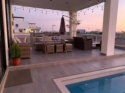 a patio with chairs and a table and a pool at Topará Beach House in San Vicente de Cañete