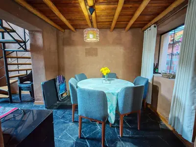 a dining room table with blue chairs and a vase of flowers at Condomino Villa Andina in Urubamba
