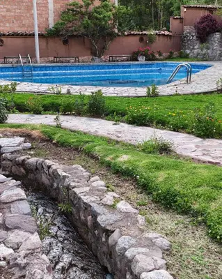 a swimming pool with a stone path leading into a yard at Condomino Villa Andina in Urubamba