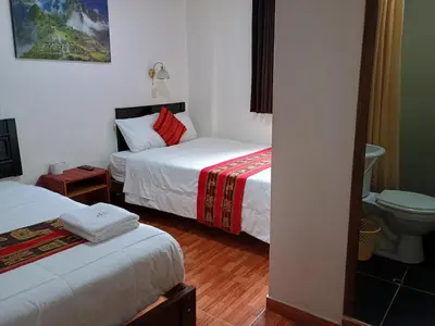 a hotel room with two beds and a toilet at Hostal Killari Machupicchu in Machu Picchu