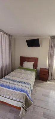 a bedroom with a bed and a tv on the wall at Hotel Los Andenes in Cotahuasi