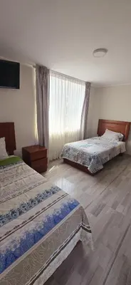 a hotel room with two beds and a window at Hotel Los Andenes in Cotahuasi