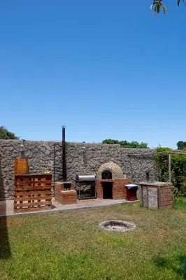 a patio with a grill and a stone wall at Las Delicias in Huacho