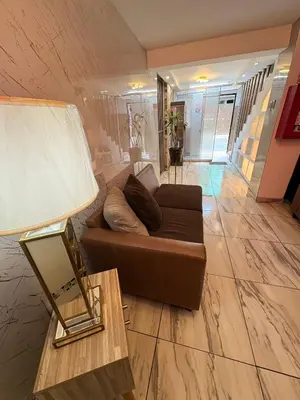 a living room with a brown couch and a mirror at Hostal Mayra Breña in Lima