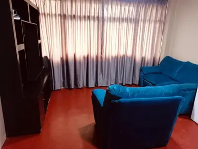 a living room with a blue couch and a window at Habitación cama dos plazas in Lima