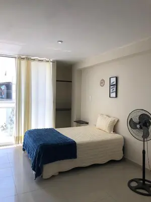 a bedroom with a bed with a blue blanket and a fan at Hotel Inkayacu Paracas Café in Paracas