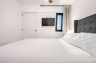 a white bedroom with a white bed and a tv at Bajada Balta Suites Spacious 3BR in Miraflores Walkable Area in Lima